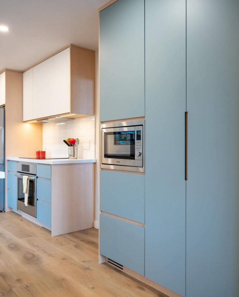 Modern kitchen with soft blue cabinetry and built-in stainless steel microwave